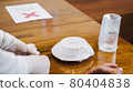 Close-up restaurant waitress serving sanitized dish, spoon and fork to Asian male customer 80404838