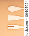 Three wooden spatulas for the kitchen on a light peach background. Bamboo kitchen tools. 80405094