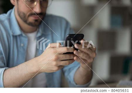 Serious man sit at desk holding cellphone solve business remotely Serious man sit at desk holding cellphone solve business remotely 80405631