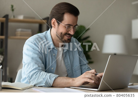 Man sit at desk texting on laptop working from homeoffice Man sit at desk texting on laptop working from homeoffice 80405635