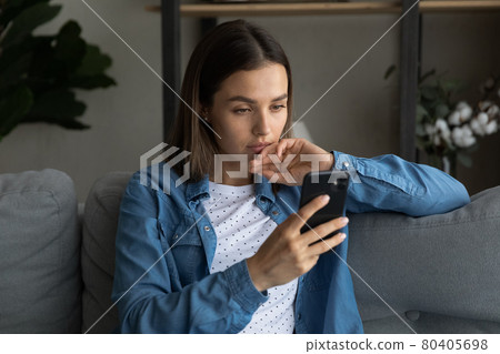 Serious woman sit on sofa read sms feels upset Serious woman sit on sofa read sms feels upset 80405698