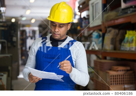 Focused salesman checking goods on shelves of construction hypermarket Focused salesman checking goods on shelves of construction hypermarket 80406186