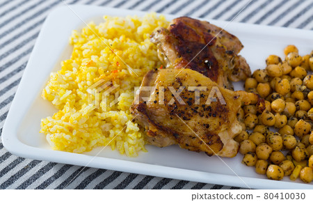 Grilled chicken thighs with garbanzo and yellow rice at plate Grilled chicken thighs with garbanzo and yellow rice at plate 80410030