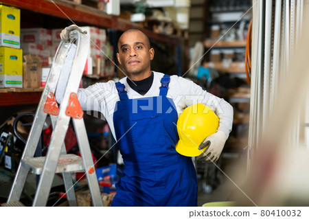 Positive Latin American workman in wareroom of construction hypermarket Positive Latin American workman in wareroom of construction hypermarket 80410032
