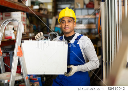 Positive latin american workman with tool suitcase in hardware store 80410042