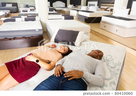 Married couple lies on a mattress, checking it for strength in store 80410060