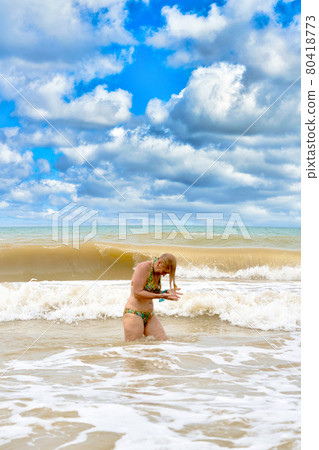 A woman in a swimsuit with white long hair comes out of the sea 80418773
