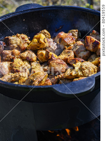 The meat is fried in a cast-iron cauldron over an open-air fire The meat is fried in a cast-iron cauldron over an open-air fire 80419559
