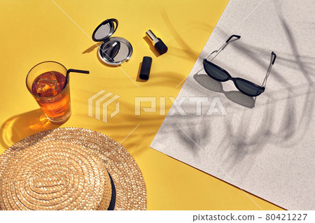 Straw beach woman's hat and sun glasses, top view yellow and white paper background with shadow from a palm leaf. Straw beach woman's hat and sun glasses, top view yellow and white paper background with shadow from a palm leaf. 80421227