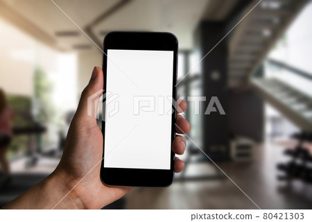 Female holding a black smartphone with a touch screen at Gym in the morning light. 80421303