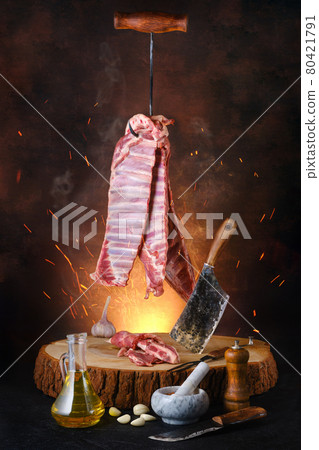 Raw lamb ribs on hook over wooden stumb 80421791