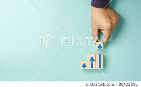 Top view arrow go up on wood block stacking same as step stair on  blue paper background, Business finance growth up concept. Success stock market . financial management achievement and investment. 80422856