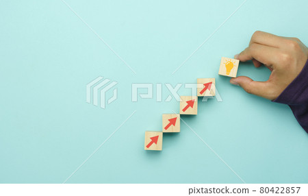 Top view arrow go up on wood block stacking same as step stair to idea bulb on blue paper background, Business growth up concept. Success stock market . management achievement goal. Strategy target. 80422857