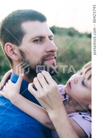 Dad and daughter play together on the flower field. Happy and caring father is having fun with his daughter. Dad pays attention to his child. Bearded man and little girl with flowers in their hair 80423745