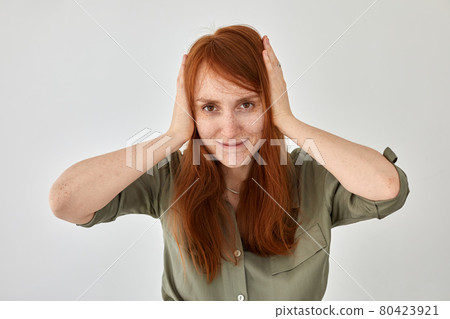 Positive red haired woman covering ears 80423921
