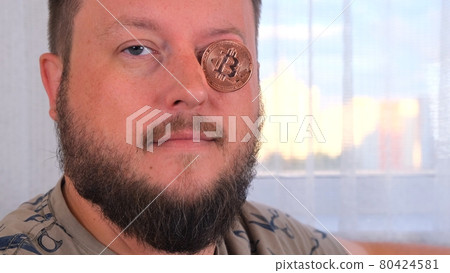 man holds bitcoins. Male with bitcoin in eye. Bitcoin is a cryptocurrency invented in 2008 by an 80424581
