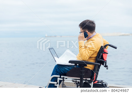 a man with disabilities in a wheelchair talking on a smartphone a man with disabilities in a wheelchair talking on a smartphone 80424987