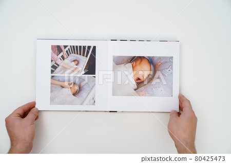 on white background, hands flip through photobook from home family photo shoot 80425473