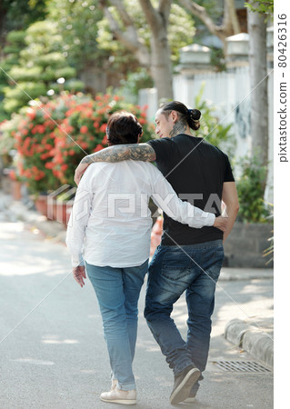 Son walking with his mother outdoors 80426316