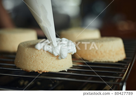 squeezes cream on a cake. Cake Decorations.. squeezes cream on a cake. Cake Decorations.. 80427789