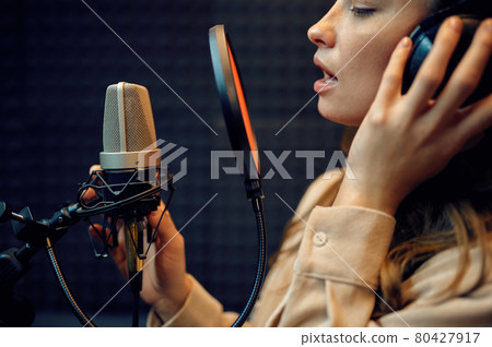 Female performer at micriphone, recording studio 80427917