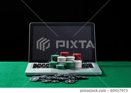 Casino chips on keyboard notebook at green table. 80427973