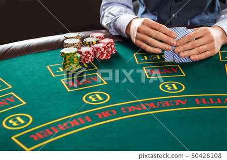 Closeup of poker player with playing cards and chips Closeup of poker player with playing cards and chips 80428108