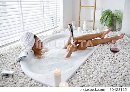Sexy young woman reads a magazine in a bubble bath Sexy young woman reads a magazine in a bubble bath 80428115