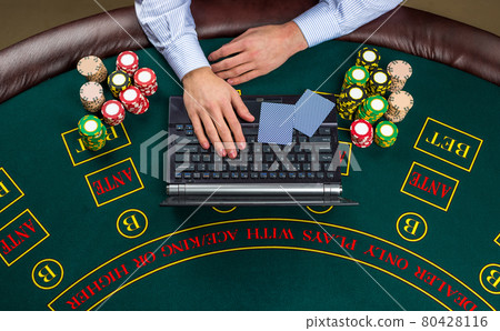 Closeup of poker player with playing cards, laptop and chips 80428116