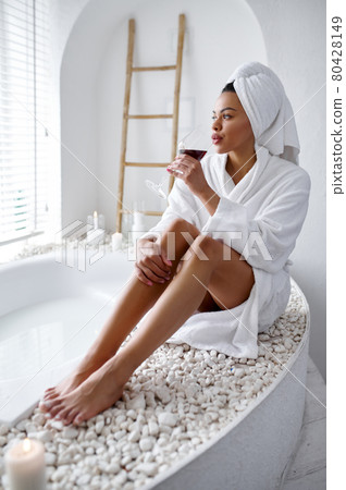 Attractive woman in bathrobe sitting near the bath Attractive woman in bathrobe sitting near the bath 80428149