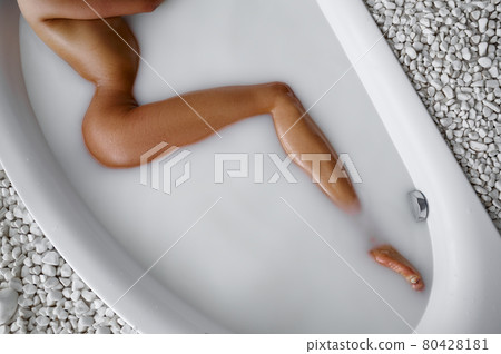 Young woman lying in bath with milk 80428181