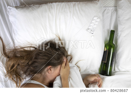 Sleeping drunk girl with empty wine bottle. Lying on the bed fainted, alcohol abuse,addiction concept top view 80428687