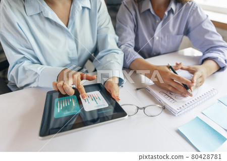 Two young women, colleguas during working day, business meeting. Using laptop, modern gadgets, notes. Workplace at office with PC, devices. Two young women, colleguas during working day, business meeting. Using laptop, modern gadgets, notes. Workplace at office with PC, devices. 80428781