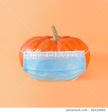 Orange pumpkin in medical mask on a beige background. Orange pumpkin in medical mask on a beige background. 80428866