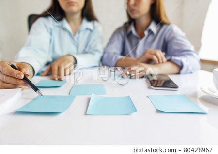 Two young women, colleguas during working day, business meeting. Using laptop, modern gadgets, notes. Workplace at office with PC, devices. Two young women, colleguas during working day, business meeting. Using laptop, modern gadgets, notes. Workplace at office with PC, devices. 80428962