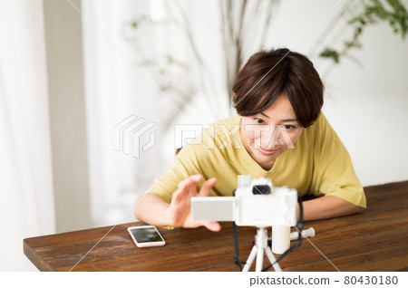A woman preparing a camera before shooting a video 80430180