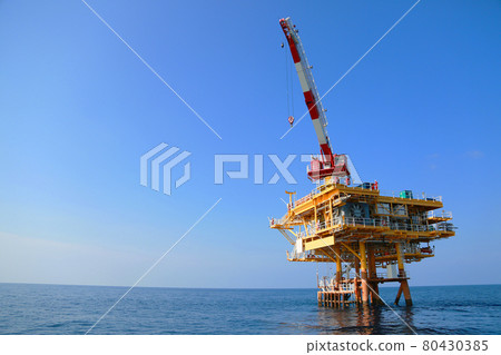Oil and gas platform standing in the gulf or offshore and operation by technician. Crane moving any cargo or tools basket from supply boat to the platform. Heavy lift was moving by crane technician. Oil and gas platform standing in the gulf or offshore and operation by technician. Crane moving any cargo or tools basket from supply boat to the platform. Heavy lift was moving by crane technician. 80430385