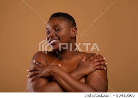 Portrait of beautiful plus size African american woman embracing herself Portrait of beautiful plus size African american woman embracing herself 80430500