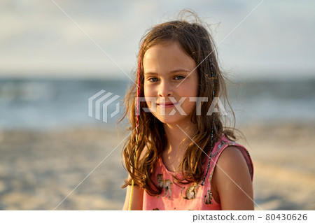 Portrait of a happy little girl on the beach during sunset Portrait of a happy little girl on the beach during sunset 80430626