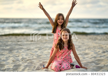 Two sisters playing on the beach at the day time. Concept of friendly sister. 80431323