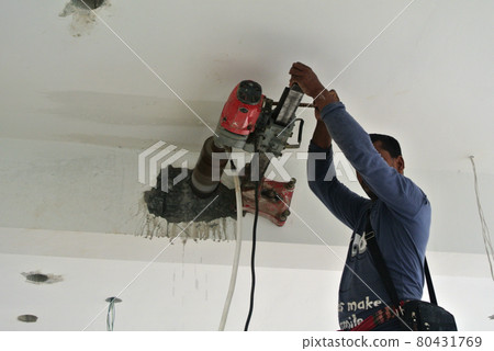 KUALA LUMPUR, MALAYSIA -DECEMBER 06, 2016: Concrete coring work by construction worker. He using coring machine to drill a hole to the concrete. KUALA LUMPUR, MALAYSIA -DECEMBER 06, 2016: Concrete coring work by construction worker. He using coring machine to drill a hole to the concrete. 80431769