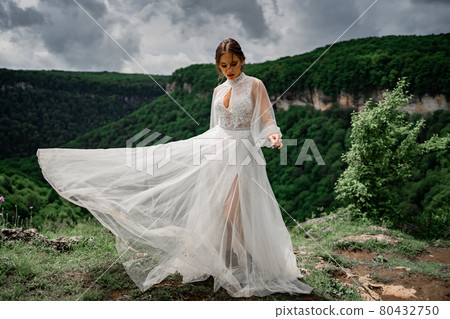 woman in a wedding dress posing in the mountains. fashionable clothes for bride 80432750