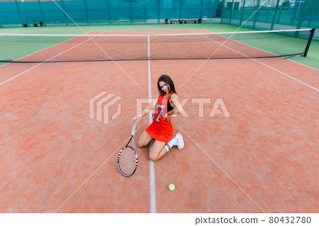 Beautiful female tennis player on tennis court. Red dress. Beautiful female tennis player on tennis court. Red dress. 80432780