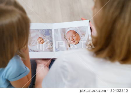 top view. mother and daughter watch photobook from discharge of newborn baby 80432840