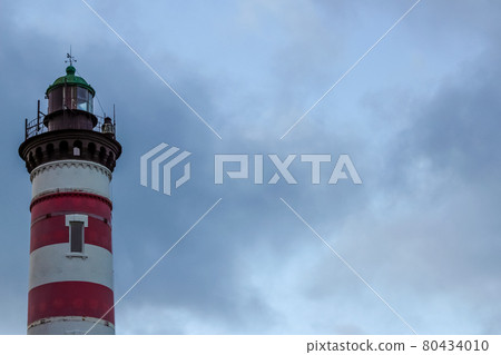 Red and white striped lighthouse on the background of a stormy sky. Free copy space for design or text Red and white striped lighthouse on the background of a stormy sky. Free copy space for design or text 80434010