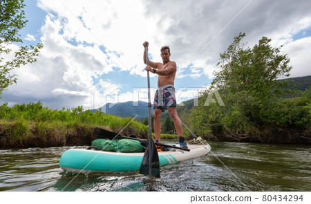 Adventurous Hispanic Adult Athletic Man paddle boarding 80434294