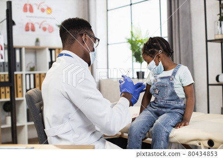 Black medical worker making injection for pretty child Black medical worker making injection for pretty child 80434853