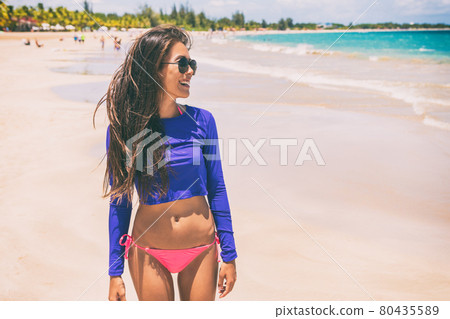 Beach rashguard bikini woman wearing swim shirt rash guard for sun protection against solar uv rays. 80435589