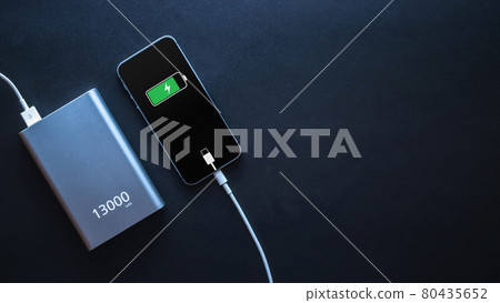 Charging power bank. Portable powerbank with white usb cable for charger mobile phone or smartphone battery. Modern technology concept in top view. Charging power bank. Portable powerbank with white usb cable for charger mobile phone or smartphone battery. Modern technology concept in top view. 80435652