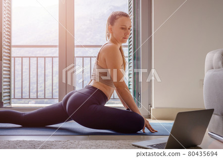 Fit woman stretching her legs in pigeon yoga pose Fit woman stretching her legs in pigeon yoga pose 80435694